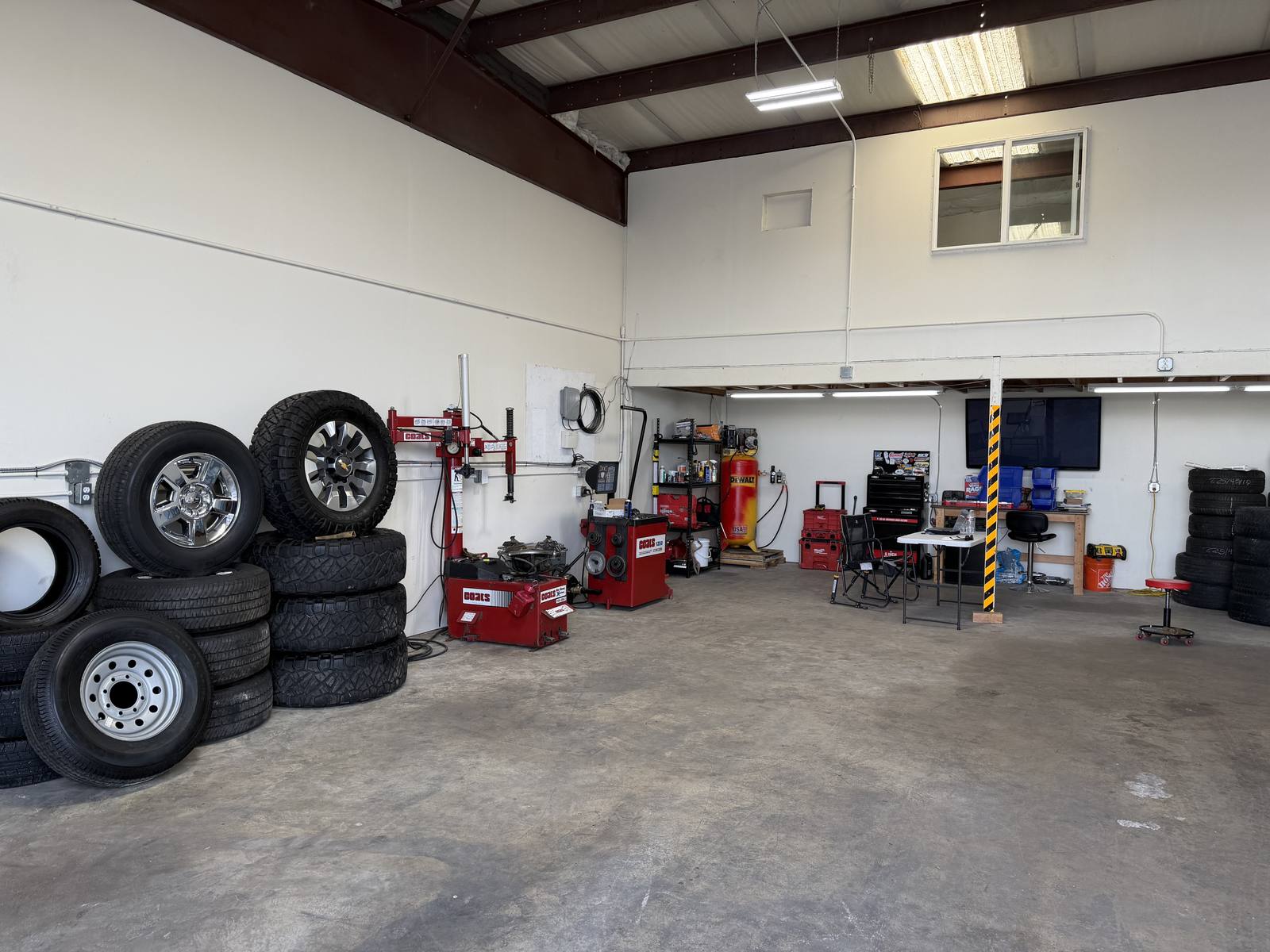 Inside the Tire Pros Shop bay in Logan, Utah — Coats tire changer and wheel balancer with stacked tires and wheels